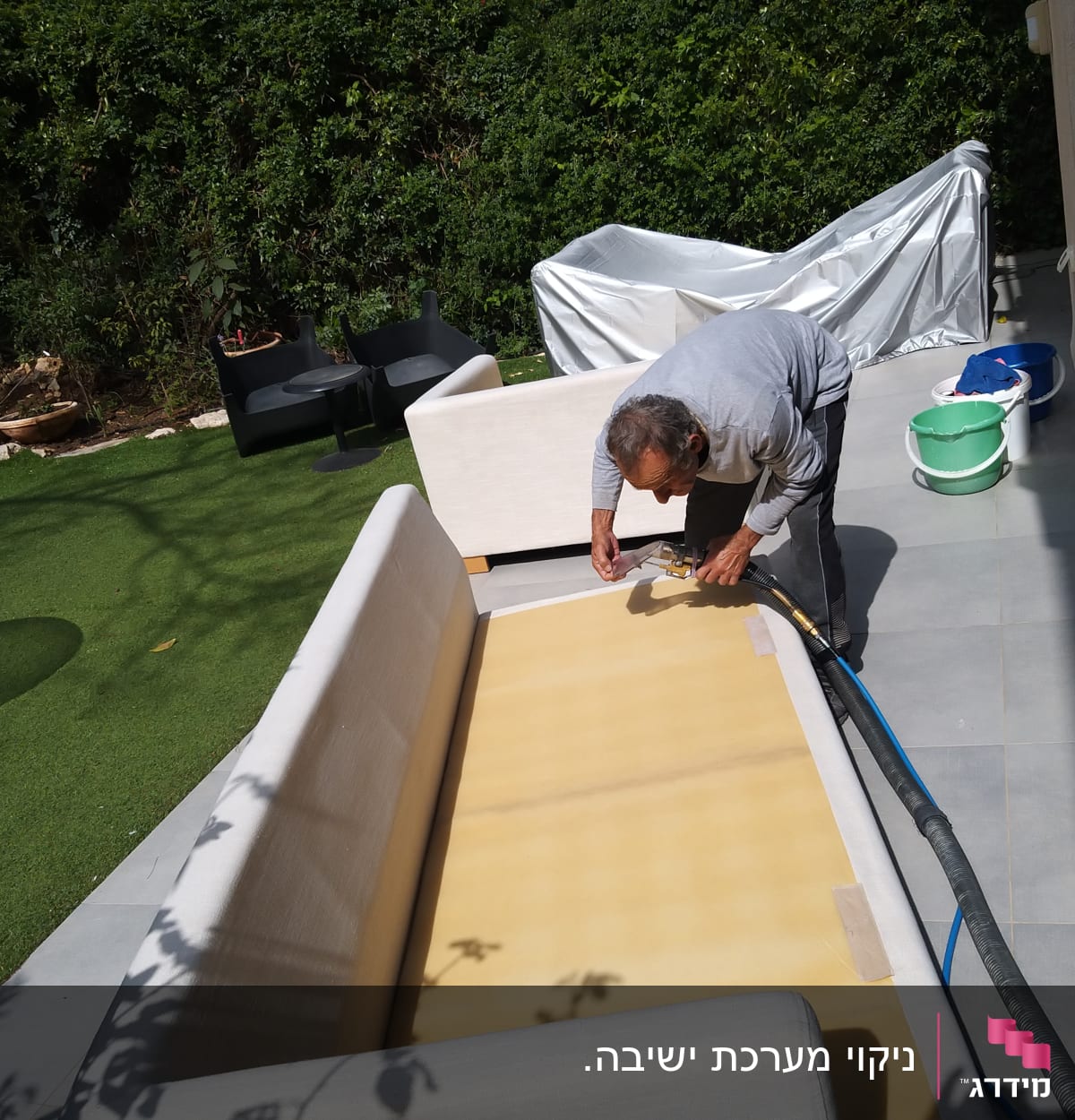 אדם מנקה ספה עם צינור ומכשיר ניקוי